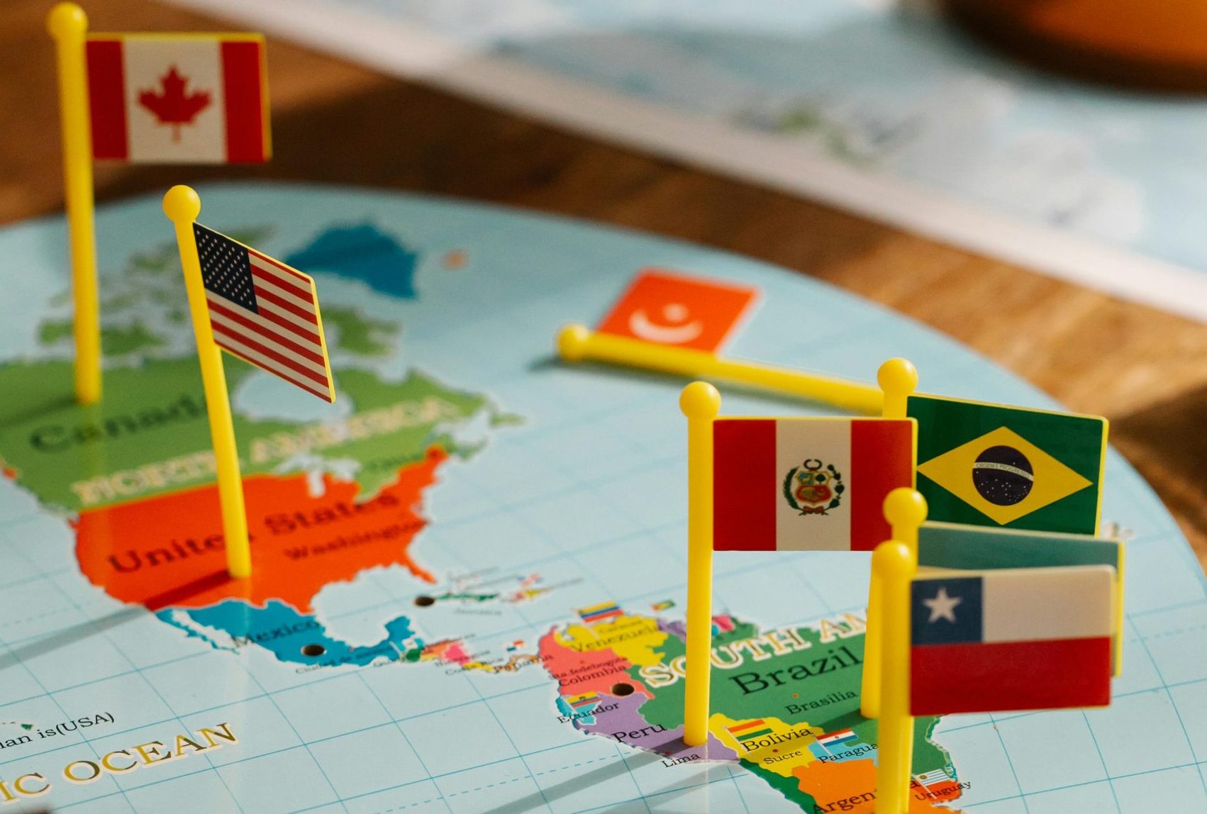 Close-up of South American map with small flags and a globe, symbolizing geography and international relations.